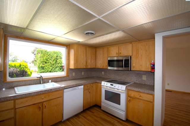 kitchen with a sink, tasteful backsplash, white appliances, and dark wood finished floors