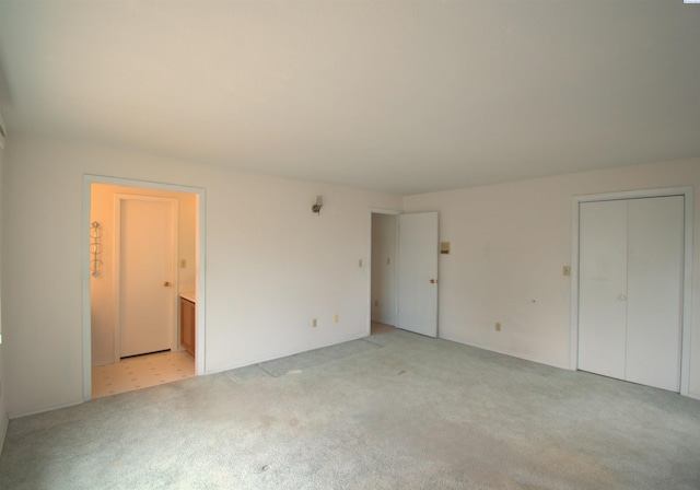 unfurnished bedroom with light colored carpet and ensuite bathroom