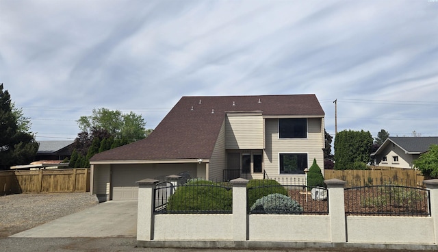 view of front of house with concrete driveway, a fenced front yard, and a garage