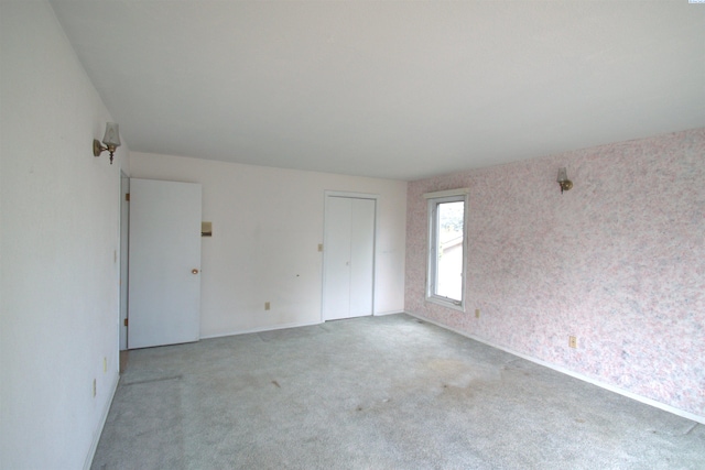 empty room featuring baseboards and light colored carpet