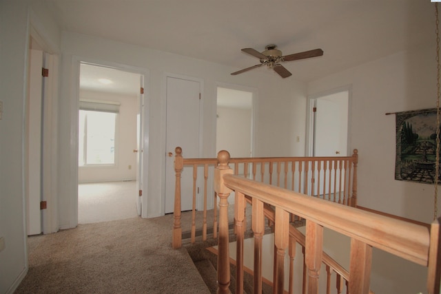 hall featuring carpet flooring and an upstairs landing
