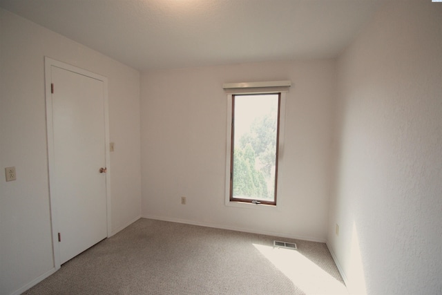 carpeted empty room with visible vents and baseboards