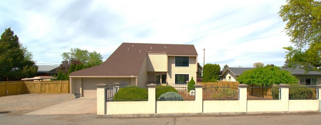view of front of house featuring an attached garage, driveway, and a fenced front yard