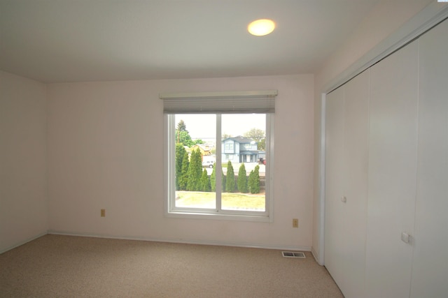 unfurnished bedroom with visible vents, light carpet, multiple windows, and a closet