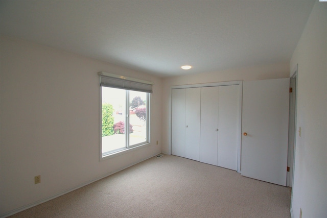 unfurnished bedroom with light colored carpet and a closet