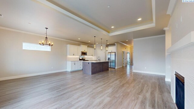 4801 White Dr, Richland, WA 99352 - unfurnished living room featuring sink, an inviting chandelier, light hardwood / wood-style flooring, a raised ceiling, and a tiled fireplace