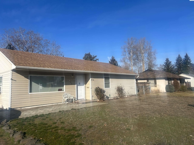 view of front facade with roof with shingles, fence, and a front lawn