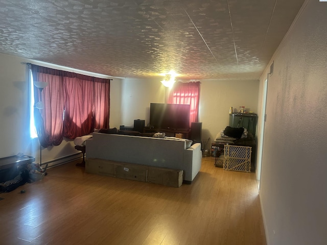 interior space with a textured ceiling, a baseboard radiator, and wood finished floors