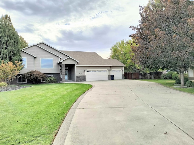 split level home featuring a front yard, fence, a garage, stone siding, and driveway