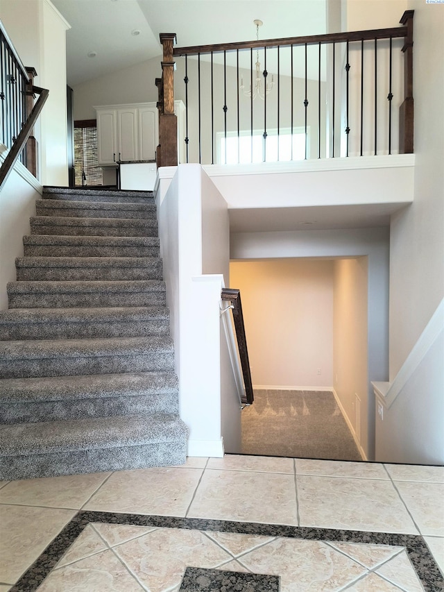 staircase with high vaulted ceiling and baseboards