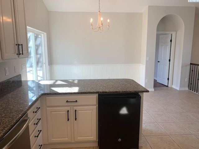 kitchen with arched walkways, a peninsula, white cabinetry, stainless steel dishwasher, and light tile patterned flooring