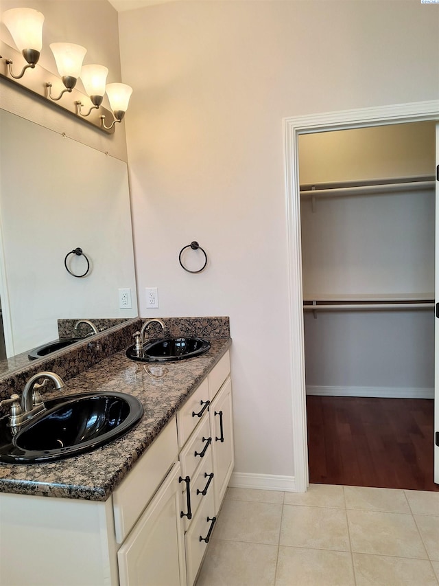 full bathroom with double vanity, tile patterned flooring, and a sink