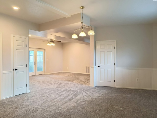 carpeted empty room with a ceiling fan, french doors, a wainscoted wall, and visible vents