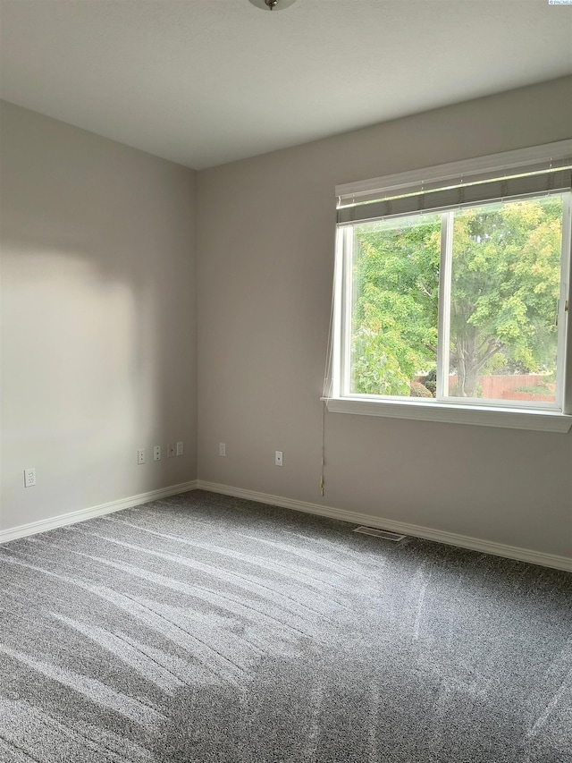 carpeted empty room with visible vents and baseboards