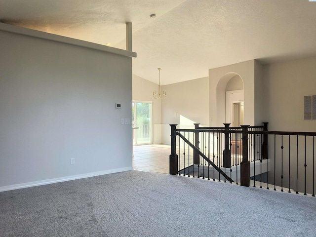 spare room featuring a textured ceiling, a notable chandelier, light carpet, baseboards, and vaulted ceiling