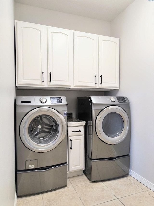 laundry room with cabinet space, baseboards, light tile patterned flooring, and independent washer and dryer