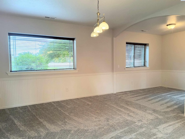 carpeted empty room featuring wainscoting, visible vents, and a healthy amount of sunlight