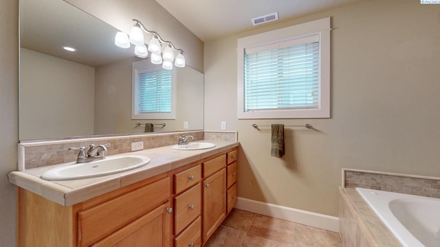 bathroom featuring tile patterned floors, vanity, and tiled bath