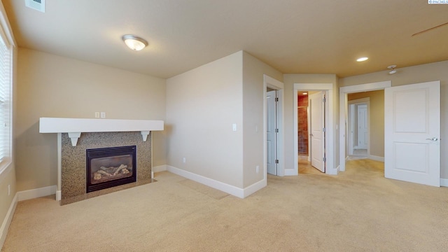 unfurnished living room featuring a tiled fireplace and light colored carpet