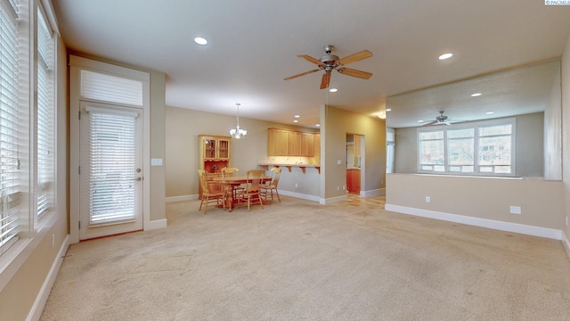 unfurnished living room featuring ceiling fan with notable chandelier and light colored carpet