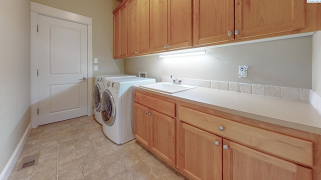 clothes washing area with cabinets, sink, and washing machine and clothes dryer