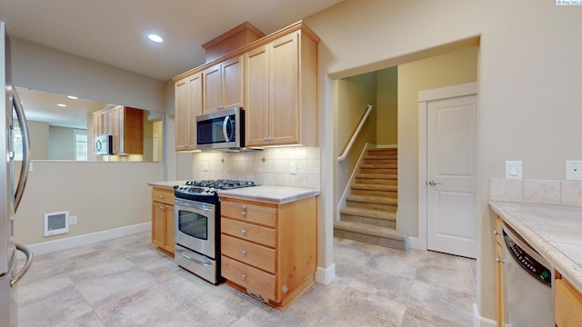 kitchen with tasteful backsplash, stainless steel appliances, and light brown cabinetry