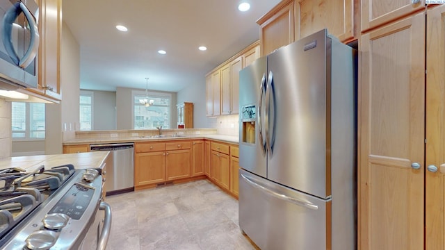 kitchen featuring decorative light fixtures, sink, kitchen peninsula, stainless steel appliances, and light brown cabinets