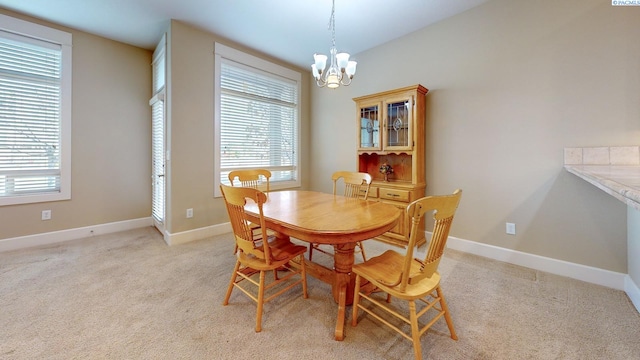 dining space featuring a notable chandelier and light colored carpet