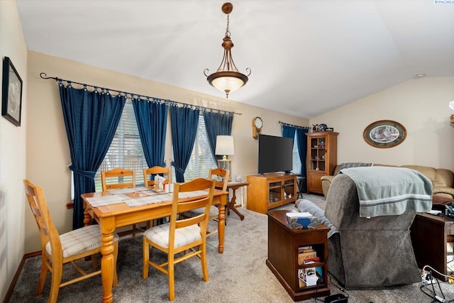 carpeted dining space with vaulted ceiling