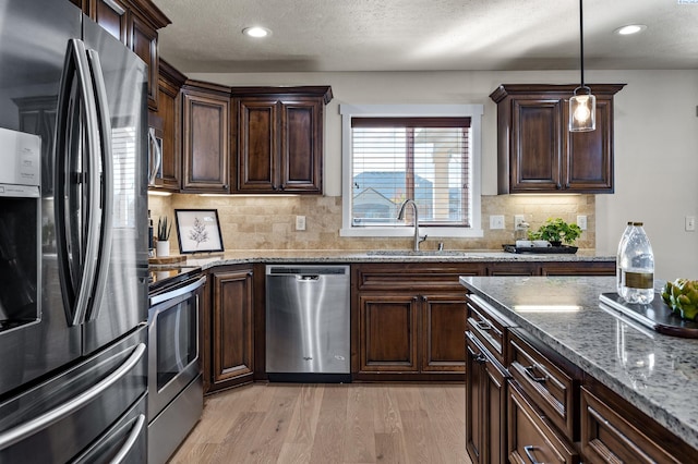 4006 Phoenix Ln, Pasco, WA 99301 - kitchen with light wood-type flooring, a sink, light stone counters, dark brown cabinets, and appliances with stainless steel finishes