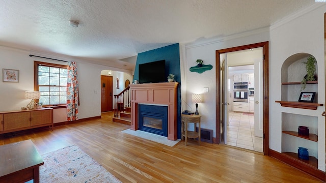 420 SE Dexter St, Pullman, WA 99163 - unfurnished living room featuring light wood-style floors, a textured ceiling, arched walkways, ornamental molding, and baseboards