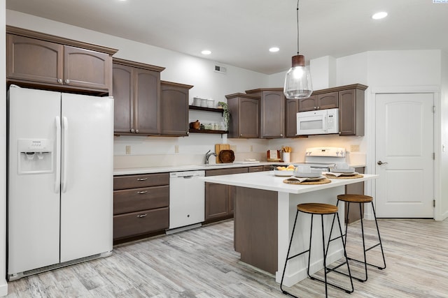 kitchen featuring hanging light fixtures, light hardwood / wood-style flooring, sink, white appliances, and dark brown cabinets