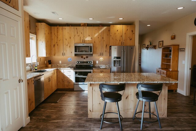 kitchen featuring stainless steel appliances, a breakfast bar, sink, and a kitchen island