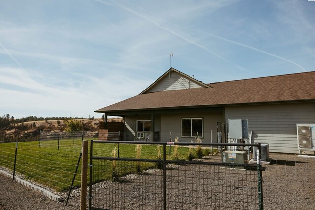 rear view of house featuring a yard, basketball hoop, and central air condition unit