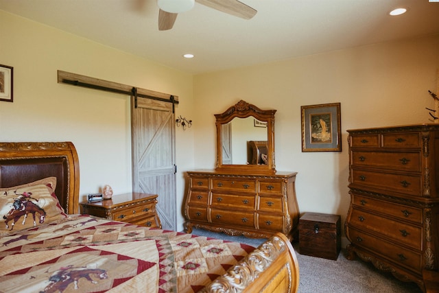 carpeted bedroom featuring a barn door and ceiling fan