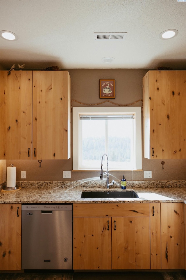 kitchen with light brown cabinetry, dishwasher, and sink