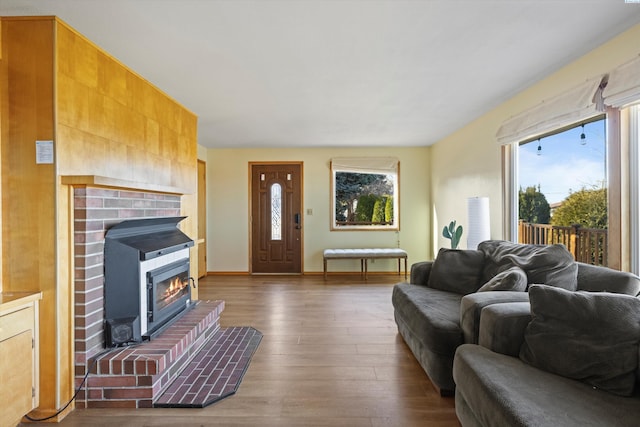 living area featuring a fireplace, plenty of natural light, wood finished floors, and baseboards