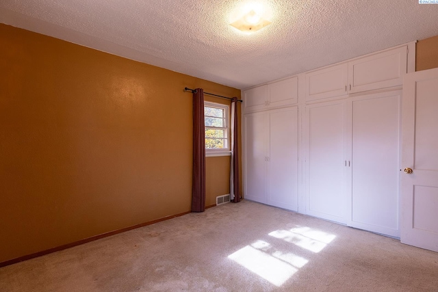 unfurnished bedroom featuring a closet, light carpet, and a textured ceiling