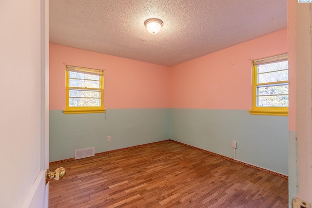 unfurnished room featuring a textured ceiling and light hardwood / wood-style floors