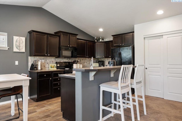 2909 S Jean St, Kennewick, WA 99336 - kitchen with black appliances, vaulted ceiling, a breakfast bar, backsplash, and light countertops