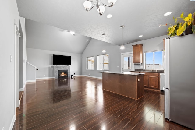 874 Pikes Peak Dr, West Richland, WA 99353 - kitchen featuring freestanding refrigerator, a center island, brown cabinetry, lofted ceiling, and a tiled fireplace