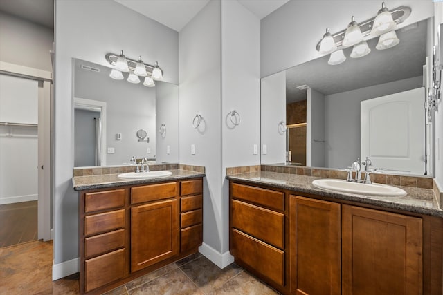 874 Pikes Peak Dr, West Richland, WA 99353 - bathroom featuring two vanities, baseboards, and a walk in closet