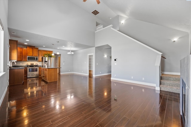 874 Pikes Peak Dr, West Richland, WA 99353 - unfurnished living room featuring high vaulted ceiling, baseboards, stairway, dark wood-style flooring, and a sink