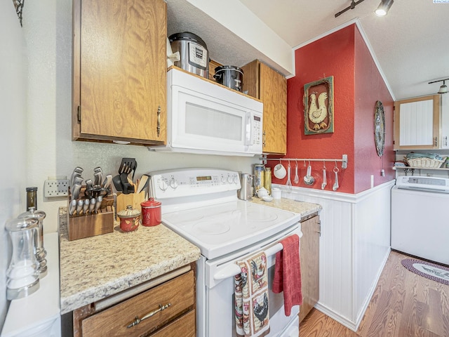 902 W 44th Pl, Kennewick, WA 99337 - kitchen with washer / dryer, white appliances, wainscoting, light wood-type flooring, and brown cabinets