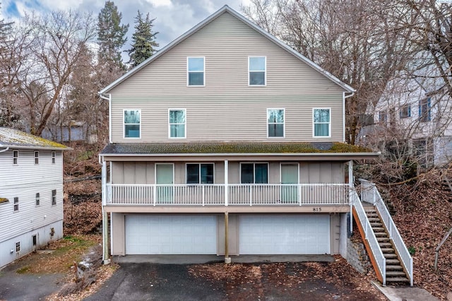 rear view of property featuring aphalt driveway, stairs, and a garage