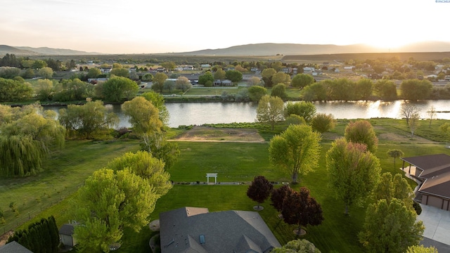 aerial view at dusk featuring a water and mountain view