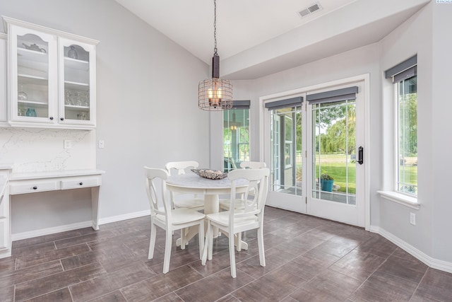 dining area featuring an inviting chandelier, plenty of natural light, vaulted ceiling, and visible vents