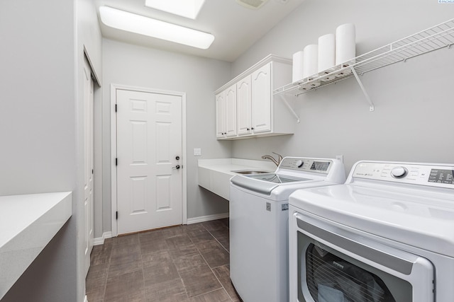 clothes washing area with a sink, baseboards, cabinet space, and washer and dryer