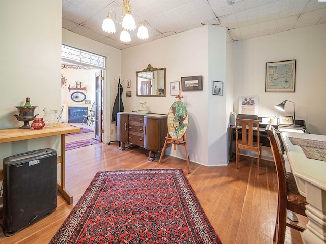 office area with hardwood / wood-style floors, a drop ceiling, and an inviting chandelier