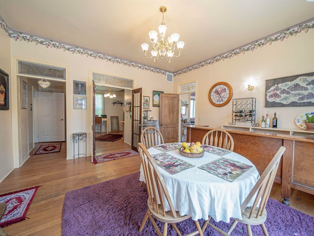 dining room with a healthy amount of sunlight, hardwood / wood-style floors, and a chandelier